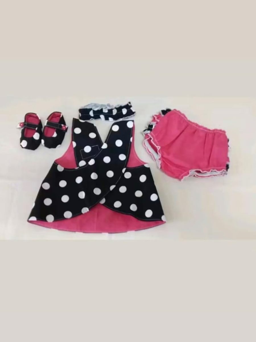 Ajuar de bebé sobre fondo claro: pichi de lunares con forro rosa, bombacho a juego, diadema y zapatitos